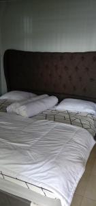 Elle comprend un grand lit avec des draps et des oreillers blancs. dans l'établissement Melbyls Hills Resort, à Tomohon