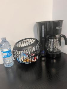 Well furnished 1 Bedroom Basement Suite في وينيبيغ: سلة على منضدة مع آلة صنع القهوة وزجاجة من الماء