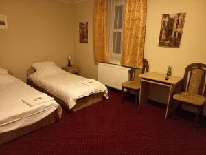 a room with two beds and a chair and a window at Pałac Lasów in Pieńsk