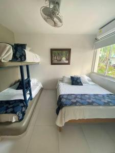 1 dormitorio con 2 camas y ventana en Cabaña Coveñitas 9, en Coveñas