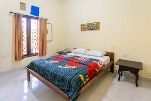 um quarto com uma cama, uma mesa e uma janela em Jero Harum Homestay em Krambitan