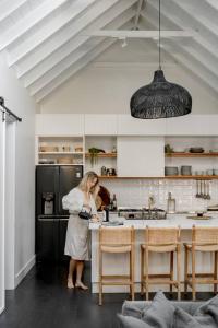 a woman standing in a kitchen preparing food at Soul of Gerringong Farmhouse in Gerringong