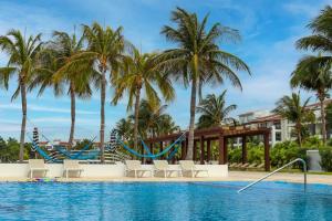 a pool at the resort with palm trees and a slide at Mareazul Beachfront Resort - Casa Ancora in Playa del Carmen