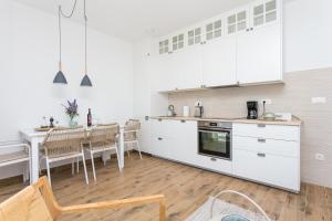 cocina con armarios blancos y mesa de comedor en Apartments by the sea Pisak, Omis - 21568, en Pisak