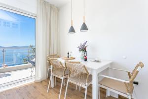 un comedor blanco con mesa, sillas y ventana en Apartments by the sea Pisak, Omis - 21568, en Pisak