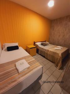 2 camas en una habitación con paredes amarillas en BC Paradise Hostel & Suítes, en Balneário Camboriú
