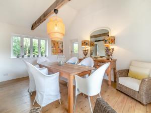 a dining room with a wooden table and white chairs at Linen Post Barn in Debenham