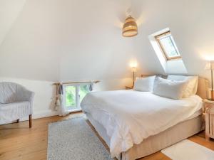 a bedroom with a white bed and a chair at Linen Post Barn in Debenham