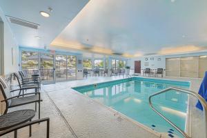 ein großer Pool mit Stühlen und Tischen in einem Gebäude in der Unterkunft Fairfield Inn & Suites by Marriott Chicago Naperville in Naperville