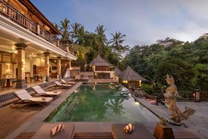 a resort pool with lounge chairs and a resort at The Pari Sudha in Ubud