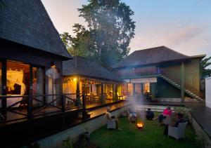 a group of people sitting on a patio in front of a house at Kolonial House in Sanur