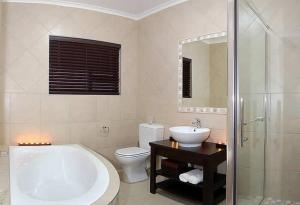 a bathroom with a tub and a toilet and a sink at Lalapanzi Guest Lodge in Port Elizabeth +10 photos