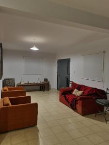 sala de estar con sofá rojo y mesa en Las Tres Herraduras - Casa de Campo en Córdoba