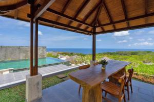 a dining room with a table and a view of the ocean at Vivo Villas - Villa Vivo in Uluwatu