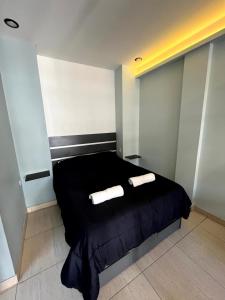 a bedroom with a black bed with two towels on it at Departamentos Muskuy - Salta Capital in Salta