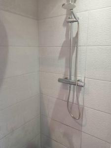 a shower with a hose in a white tiled bathroom at Petit coin de paradis in Baie Nettle