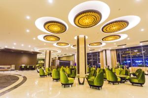 a lobby of a hotel with green chairs and lights at Muong Thanh Luxury Can Tho Hotel in Can Tho