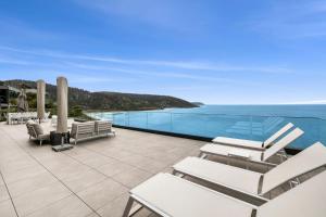 un patio con sillas blancas y vistas al océano en Cape Wye en Wye River