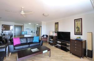 a living room with a couch and a tv at Coral Sands Penthouse in Bargara