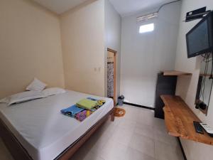 a bedroom with a bed with a television and a table at Azza karimunjawa in Karimunjawa