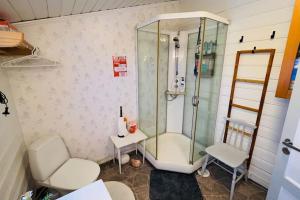a bathroom with a shower and a toilet and a chair at GuestHouse Seiland in Skakkebakken