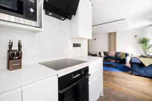 eine Küche mit weißen Schränken und einem Waschbecken sowie ein Wohnzimmer in der Unterkunft First Class Living Experience Luxury In Harley St in London