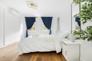 ein weißes Schlafzimmer mit einem weißen Bett und blauen Vorhängen in der Unterkunft First Class Living Experience Luxury In Harley St in London