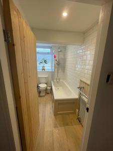 Un baño con bañera, inodoro y ventana. en Hilltop House, en Whitby
