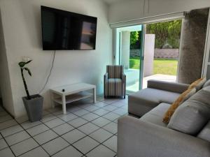 sala de estar con sofá y TV en la pared en Club de golf Santa Fe: amplia casa en el mejor clima, en Alpuyeca