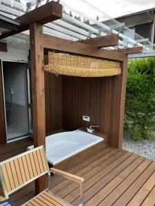 bañera de hidromasaje en una terraza de madera con banco en 下呂スプリングスロッジ en Gero