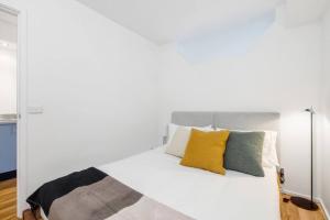 uma cama branca com almofadas amarelas e verdes em 'Melbourne Chic on Russell' Cosy City Living em Melbourne