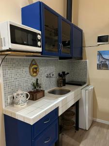 La cuisine est équipée de placards bleus, d'un évier et d'un four micro-ondes. dans l'établissement Noah Apartment, à Tbilissi