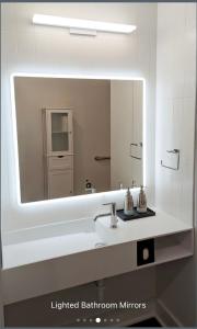 een badkamer met een grote spiegel en een witte wastafel bij The Vinyl Suite on Music Row in Nashville