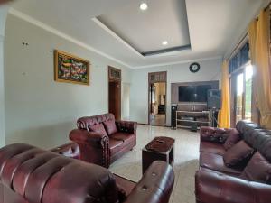 a living room with leather furniture and a flat screen tv at villa romi in Puncak