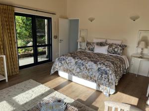 a bedroom with a bed and a large window at Kākā Ridge Retreat Luxury Cottage in Tawharanui