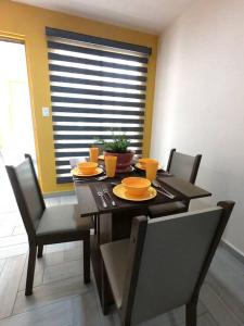 uma sala de jantar com uma mesa e cadeiras com pratos de laranja em Nuevo y Hermoso Departamento Pachuca em Mineral de la Reforma