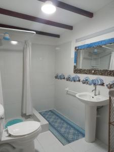 een badkamer met een wastafel, een toilet en een spiegel bij Hosteria SR in Pedernales