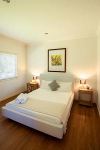 ein Schlafzimmer mit einem großen weißen Bett mit zwei Tischen in der Unterkunft Emma's Cottage Vineyard in Lovedale