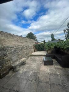 a stone wall with two benches and a brick wall at Epworth Cottage in Crich