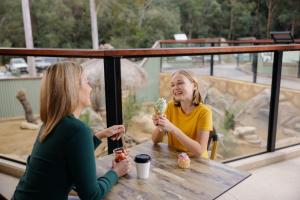Duas raparigas sentadas numa mesa a comer gelado. em Paradise Country Farmstay em Gold Coast