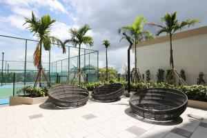 a group of metal chairs sitting on a patio with palm trees at Bali Residences @ Icon Stay Melaka in Melaka