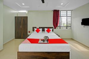 una camera da letto con un grande letto con una coperta rossa di OYO VRK Residency a Kurmannapalem