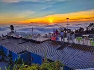 Gente parada en lo alto de un edificio mirando la puesta de sol en สเตชั่นภูทับเบิก-บ้านดาดฟ้าทะเลหมอก, en Ban Tha Kok Hai