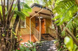 a wooden house with a front porch and stairs at A'a- Hale Kumu La'au in Volcano