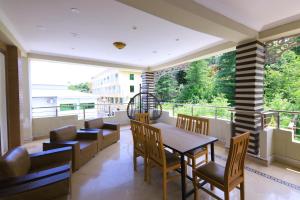 a dining room with a table and chairs and a balcony at Candle Wood in Bhurban