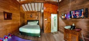 a bedroom with a bed in a room with wooden walls at joglo house karinduaji madasari in Bulakbenda