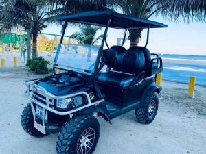 a black golf cart parked on the beach at Coastal Bay Suite & Golf Cart Rental in San Pedro