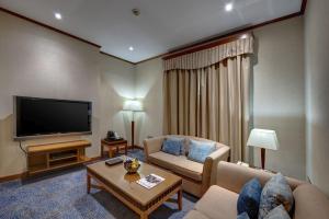 a living room with a couch and a flat screen tv at Orchid Hotel Al Barsha "Formerly Golden Tulip Hotel Al Barsha" in Dubai