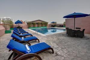 a row of lounge chairs next to a swimming pool at Golden Tulip Hotel Al Barsha in Dubai