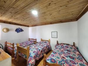 a bedroom with two beds and a wooden ceiling at Arriendo Los Vilos, Central in Los Vilos